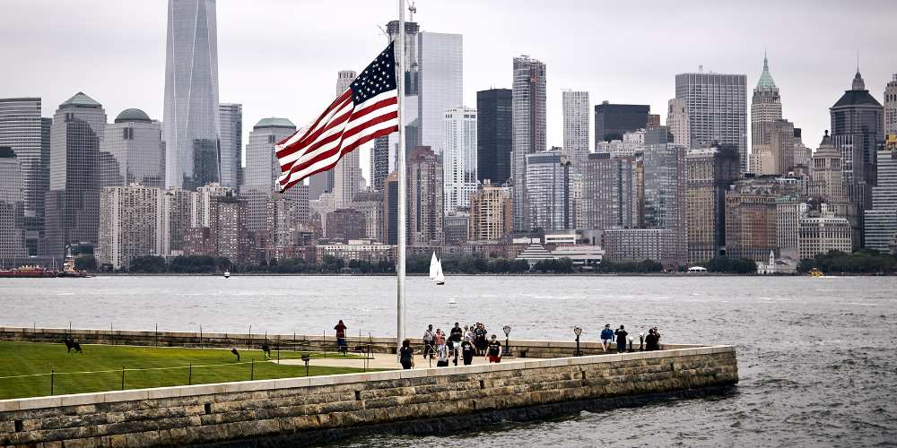 Bandera de Estados Unidos ondeando frente al skyline de Nueva York.
